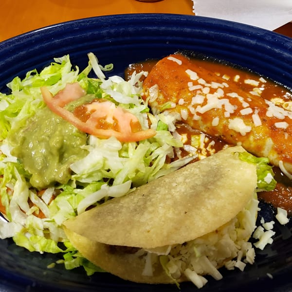 A Los Gallos Mexican Grill combo plate with a taco, enchilada, lettuce, guacamole, and tomato.
